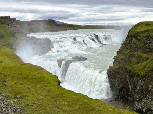 El curso del río Hvitá está condicionado por fracturas de distinta orientación que atraviesan Islandia. En este caso, se trata de fallas de deslizamiento con compresión de bloques con movimientos horizontales. Las fracturas que aparecen en las cataratas son fallas normales en las que se han deslizado los bloques uno respecto al otro. Las pequeñas cascadas del escalón superior están formadas por lavas interglaciares muy resistentes a la erosión que alternan con rocas sedimentarias erosionables de época glaciar, mientras que los basaltos columnares forman el escalón inferior y las paredes del cañón. (Autor: Antonio P. López)