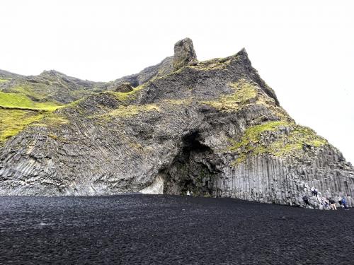 Los procesos volcánicos que formaron el acantilado subglacial son evidentes en la playa de Reynisfjara. La erosión de las olas ha dejado al descubierto un detallado resumen de su génesis. Lo más destacado son las columnas basálticas de forma poligonal que aparecen en la base del acantilado. Una intrusión horizontal de magma basáltico que fluye entre 1.200-1.300°C se enfría gradualmente hasta alcanzar unos 800°C, a partir de ahí comienza un lento proceso de solidificación. Durante el enfriamiento, el basalto se contrae y disminuye su volumen provocando que se formen una serie de fracturas o diaclasas más o menos verticales, denominadas disyunción columnar, formando las típicas columnas de basalto. El tamaño de estas columnas poligonales, generalmente de cinco o seis lados, viene determinado por la velocidad de enfriamiento del magma, siendo las mayores las formadas por enfriamientos más lentos. 
En el centro de la imagen hay una cueva, llamada Hálsanefshellir, producto de la erosión provocada por las olas en las columnas de basalto. (Autor: Antonio P. López)