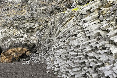 A la derecha, grupo de finas columnas de basalto. A la izquierda y de color ocre, ‘pillow lavas’ o lavas almohadilladas, formadas cuando el magma es expulsado en una zona con agua. Debido a la enorme diferencia de temperatura entre la lava y el agua, la superficie de la lengua emergente se enfría muy rápido, formando una corteza. La lengua continúa creciendo e hinchándose con más lava, formando un lóbulo, hasta que la presión del magma rompe la corteza y comienza de nuevo el proceso con la formación de otro lóbulo. En la parte superior, hialoclastitas y tobas. (Autor: Antonio P. López)