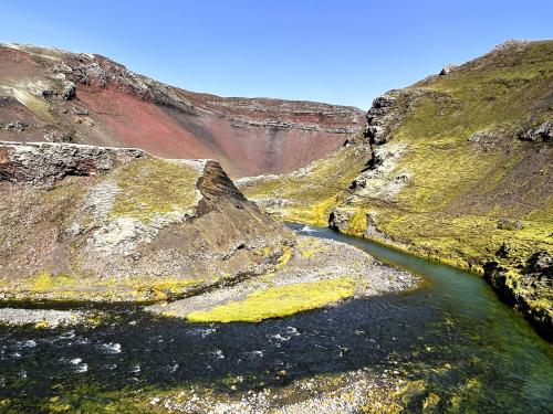 El río Hólmsá recibe sus aguas desde el norte del Mýrdalsjökull, el glaciar que cubre el volcán activo Katla. En la foto, un meandro del río Hólmsá que bordea el cráter rojizo del volcán Rauðibotn (al fondo se aprecia una parte de la caldera) en donde recibe su afluente el Brennivínskvísl. (Autor: Antonio P. López)