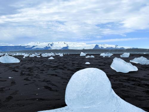 La playa Eystri-Fellsfjara de arena negra, como casi todas en Islandia, salpicada de trozos de hielo glaciar. Al fondo, el glaciar Vatnajökull que mide unos 150 km de este a oeste y unos 100 km de norte a sur. Bajo el glaciar está el volcán Öræfajökull, de 2.109,60 metros sobre el nivel del mar, que sigue activo. (Autor: Antonio P. López)