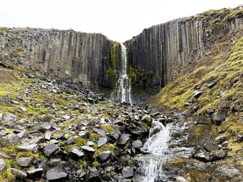 Stuðlafoss es una espectacular cascada sobre columnas basálticas que se encuentra muy cerca del cañón Stuðlagil, en el valle Jökuldalur, al este de Islandia. Las columnas de basalto están perfectamente alineadas y en posición vertical, con una altura de más de 20 metros. La roca fundida expulsada a la superficie comienza a enfriarse expuesta a las condiciones ambientales. Este enfriamiento provoca que se contraiga y se desarrollen fisuras que se extienden desde la superficie hacia el interior del flujo. Estas fisuras se forman perpendicularmente a la superficie de enfriamiento y dan como resultado la característica forma poligonal de las columnas de basalto. (Autor: Antonio P. López)