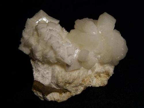 Chabazite + stilbite + mordenite
Sgurr nam Boc, Isle of Skye, Scotland, UK
Specimen measures 8cm wide x 6cm high x 4cm deep
Chabazite crystals to 13 mm on edge

Simple chabazite crystals to 13mm on edge, lustrous but with a lot of internal crazing, sit next to a group of ’cauliflower’ stilbites, all on a bed of mordenite. ( Mordenite is generally a rare mineral but it does occur at Sgurr nam Boc, with other silica-rich zeolites and of course quartz. Specimen measures 8cm wide x 6cm high x 4cm deep. Self-collected 1996 from Sgurr nam Boc, Isle of Skye. (Author: Mike Wood)