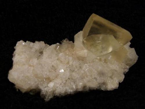 Calcite + chabazite. A not-so-good photo showing a nice yellowish transparent calcite rhomb to 15mm on edge, on a bed of small chabazite crystals. Specimen is 50mm x 25mm x 22mm. Self-collected 1999 from Moonen Bay, Duirinish, Isle of Skye. (Author: Mike Wood)