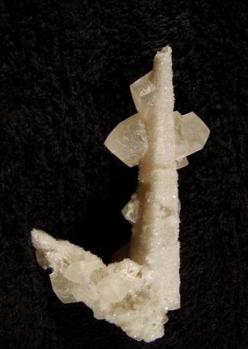 Calcite + stilbite. An elongated scalenohedron of calcite 64mm long is coated with micro stilbites, with a few rhombohedral calcites aesthetically perched on the larger crystal. Self-collected 1999 from Camas na h-Uamha, Duirinish, Isle of Skye. (Author: Mike Wood)