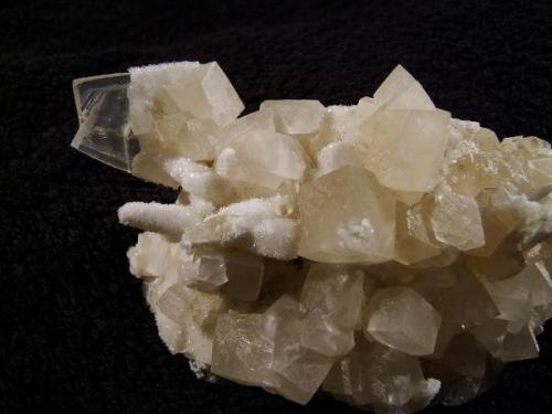 Calcite + stilbite. The only decent specimen showing the third habit of calcite at this locality. A ’butterfly’ twinned and flattened scalenohedral crystal measuring 25mm x 19mm is partially coated with micro stilbites, as is the more common elongated scalenohedral ’dog-tooth’ habit of crystal. The later more simple rhombohedral calcites appear to have been deposited after the earlier forms af calcite were covered with the micro stilbite crystals. Specimen measures 80mm wide (not all shown in the photo) x 45mm high x 40mm deep. Self-collected 1998 from Camas na h-Uamha, Duirinish, Isle of Skye. (Author: Mike Wood)