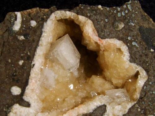 Chabazite + phillipsite. A 6mm white chabazite crystal of simple habit rests in a vug lined with lustrous brown phillipsite crystals. Vug measures 25mm wide x 22mm high. Self-collected 1996 from Moonen Bay, Isle of Skye, Scotland. (Author: Mike Wood)