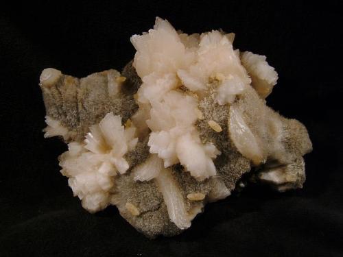 Laumontite
’Glen Caladale’, Loch Eynort, Isle of Skye, Scotland, UK
8cm x 6cm x 2cm
Laumontite on ’mesolite’ with a few scattered brown calcite crystals (to 3mm). From the same locality as one shown previously which is dry and kept in a plastic box. This specimen has been kept in water and is still fairly fresh.
The locality is on the north side of Loch Eynort on a wave-cut platform with large boulders on it.
Self-collected 1996. (Author: Mike Wood)