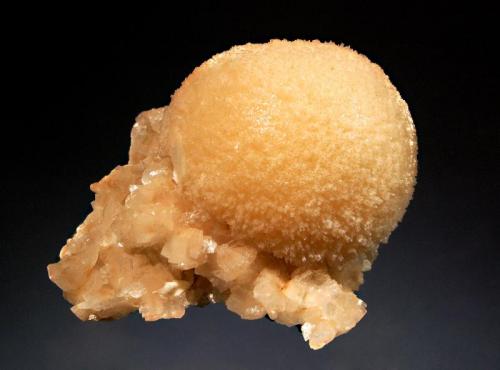 Mesolite
Kannad, Aurangabad District, Maharashtra, India
7.6 x 8.2 cm.
Light tan sphere of mesolite with with small pinkish-tan heulandite crystals on brown basalt. Collected in 2009. (Author: crosstimber)