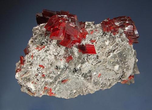 Realgar
Jiepaiyu Mine, Shimen, Changde Pref., Hunan Prov., China
4.5 x 6.4 cm.
Lustrous cherry-red realgar crystals on a silicified gray matrix with small tufts of acicular white picropharmacolite. (Author: crosstimber)