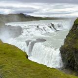 El curso del río Hvitá está condicionado por fracturas de distinta orientación que atraviesan Islandia. En este caso, se trata de fallas de deslizamiento con compresión de bloques con movimientos horizontales. Las fracturas que aparecen en las cataratas son fallas normales en las que se han deslizado los bloques uno respecto al otro. Las pequeñas cascadas del escalón superior están formadas por lavas interglaciares muy resistentes a la erosión que alternan con rocas sedimentarias erosionables de época glaciar, mientras que los basaltos columnares forman el escalón inferior y las paredes del cañón. (Autor: Antonio P. López)