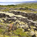 Al sur de Þingvellir está el lago Þingvallavatn, el mayor de Islandia, con 83,7 km2 y una profundidad máxima de 115 metros. Su cuenca se formó por un conjunto de fallas, hundimientos y erosión glaciar, y fue modificada por la actividad volcánica. Sus aguas son alimentadas por el río Öxará que nace en el glaciar Langjökull, a unos 50 km al norte, y por manantiales y acuíferos de aguas subterráneas.
En primer término, una serie de fracturas subparalelas cubiertas de musgo y líquenes. Al fondo, el lago Þingvallavatn. (Autor: Antonio P. López)