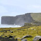 Los acantilados de Reynisfjall, cerca del pueblo de Vík í Mýrdal, al sur de Islandia, se formaron a partir de una fisura submarina en el Cinturón Volcánico Oriental, en el sistema volcánico Katla, a finales del Pleistoceno. Con una altitud de 120 metros, están constituidos por una alternancia de rocas ígneas extrusivas e intrusivas que indican que se formaron en varias fases eruptivas. En la base aparecen ‘pillow lavas’ y columnas de composición basáltica, seguidas de tobas volcánicas, a menudo con intrusiones, y en la parte superior capas de lava. Originalmente era una isla antes de convertirse en una península, unida al continente en el Holoceno, por la combinación de procesos fluviales, glaciares, volcánicos y marinos.
En la base de los acantilados aparecen unos arcos que se formaron a partir de cuevas marinas y por la acción erosiva de las olas. El más conocido es el Dyrhólaey. (Autor: Antonio P. López)