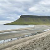 Búlandshöfði es un cabo entre Eyrarsveitar y Fróðársveitar, en la península de Snæfellsnes, al oeste del país. Con una altura total de 326 metros, las rocas basálticas que forman su base corresponden a erupciones de entre 7 y 8 millones de años. Tras un largo ciclo erosivo, hubo un periodo de sedimentación en el que aparecen fósiles de bivalvos, aproximadamente a 135-180 metros, en unos niveles con 1,1 millón de años denominados ‘Formación Búlandshöfði’. Sobre estos depósitos marinos hay algunas coladas de lava expulsadas durante la glaciación Würm, mezcladas con tobas, sedimentos y fragmentos rocosos erosionados por los glaciares, que forman la parte superior del acantilado.
En los primeros años del siglo XX, Helgi Pjetursson (que fue el primer islandés en doctorarse en Geología, en 1905) presentó una teoría revolucionaria en la geología mundial. Su teoría se basaba en que la ‘Edad de Hielo’ (glaciación Würm) no habría sido un invierno frío continuo, sino que hubo periodos cálidos entre periodos fríos que duraron entre diez y veinte mil años. Estas conclusiones las fundamentó con el estudio exhaustivo de los fósiles de la ‘Formación Búlandshöfði’, especialmente con el bivalvo ‘Portlandia arctica’ (antes ‘Yoldia arctica’) que necesita agua salada fría para vivir, y otros niveles con bivalvos marinos de aguas más cálidas. (Autor: Antonio P. López)