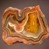 Chalcedony var. agate
Chubut Province, Argentina
6.5 x 7.2 cm.
Colorful, polished section of "condor" agate with strong fortification bands on the outer edge and colorless crystalline quartz in the center. (Author: crosstimber)