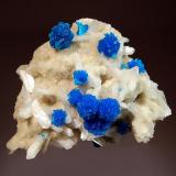 Cavansite
Dhoot Quarry, Wagholi, Pune District, Maharashtra, India
6.5 x 8.8 cm.
Spherical aggregates of cavansite to 1.0 cm in diameter scattered over a drusy stilbite matrix interspersed with white bladed stilbite crystals to 1.5 cm. (Author: crosstimber)