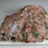 Granito miarolítico
Wimmer’s Quarry, plutón Nine Mile, Complejo de Wausau, Marathon County, Wisconsin, Estados Unidos
7 x 6 cm.
Un granito miarolítico, es decir, con cavidades irregulares (drusas) en las que se depositan diversos minerales o productos de alteración.  Aquí parecen ser cloritas junto a los grandes granos de cuarzo y feldespato rosado.  A veces se emplea la expresión "rotten granites" (granitos podridos). (Autor: prcantos)